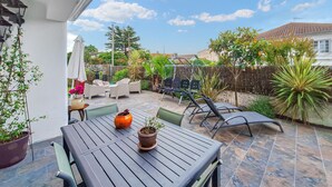 A patio with a table and chairs, surrounded by potted plants and a fence. - Belle maison rénovée (Dax)
