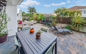 A patio with a table and chairs, surrounded by potted plants and a fence. - Belle maison rénovée (Dax)