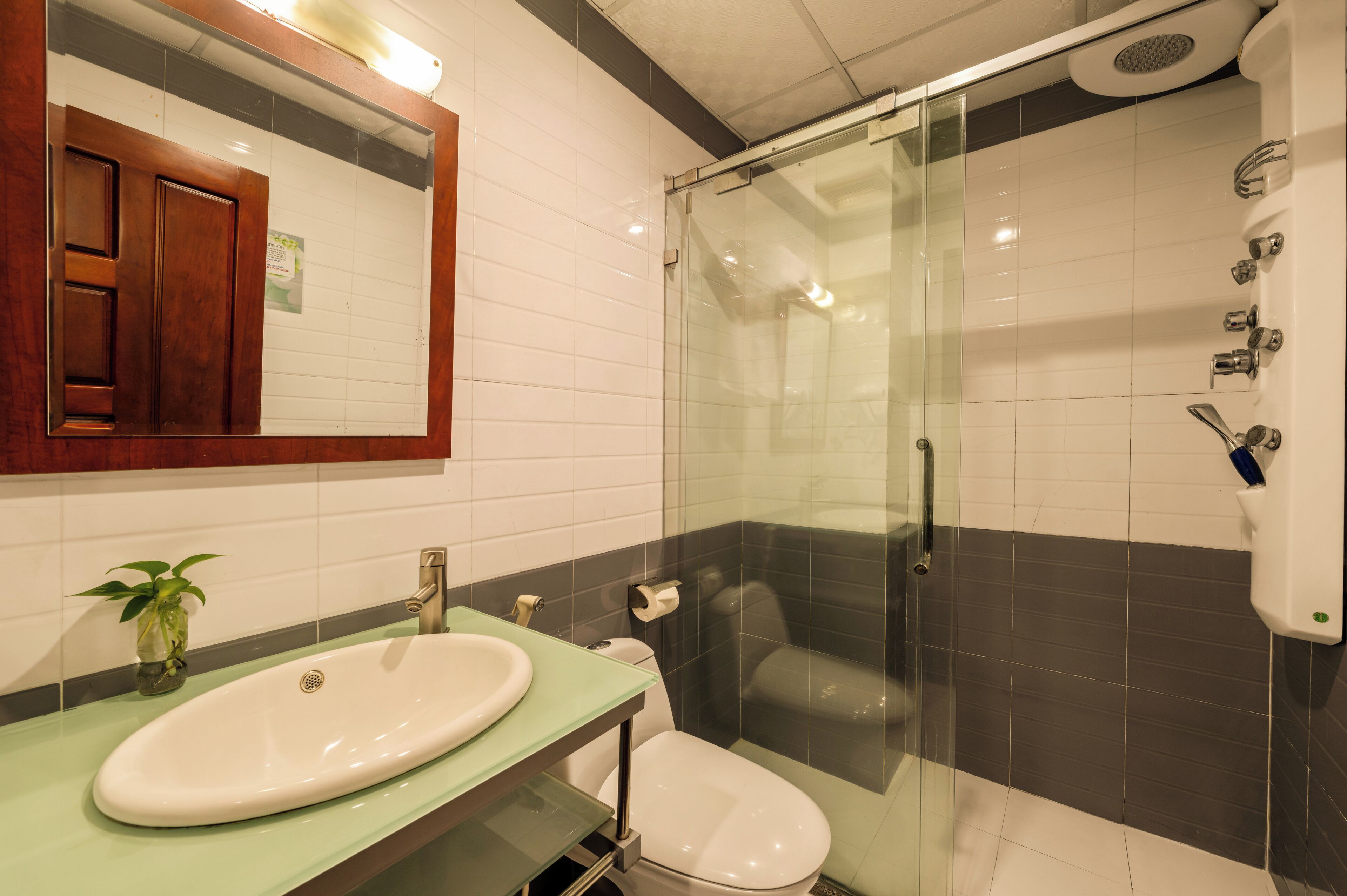 Un baño con ducha de vidrio, lavamanos y retrete.