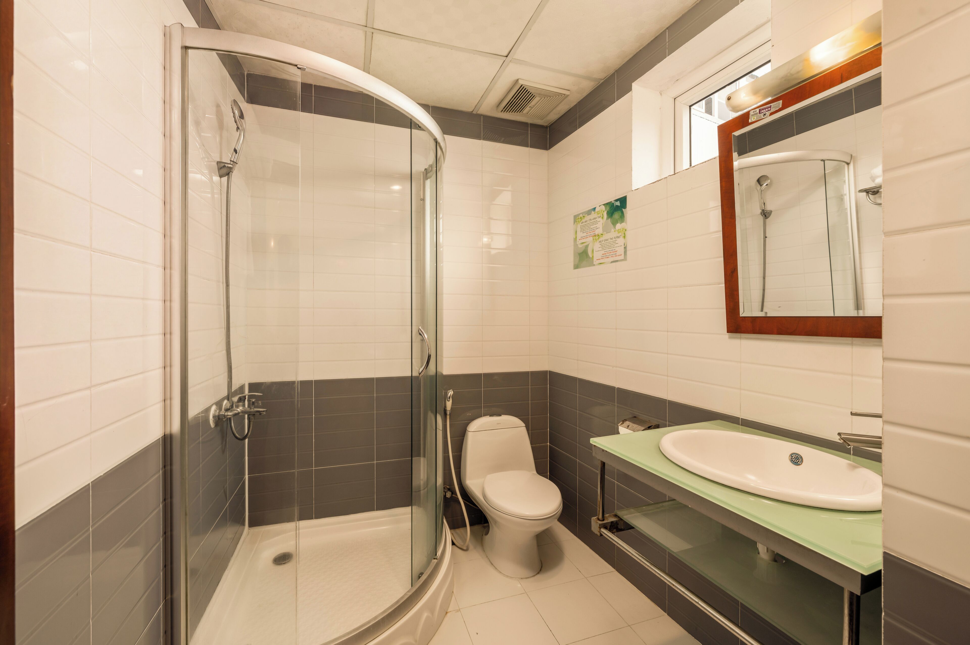 A bathroom with a glass-enclosed shower, a toilet, and a sink with a mirror above it.