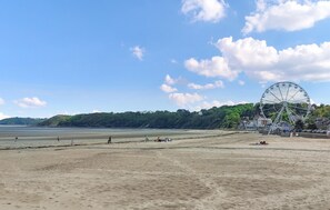 A beach with a Ferris wheel, sandy shore, and a forested hill in the background. - Studio proche de la mer (Saint-Quay-Portrieux)