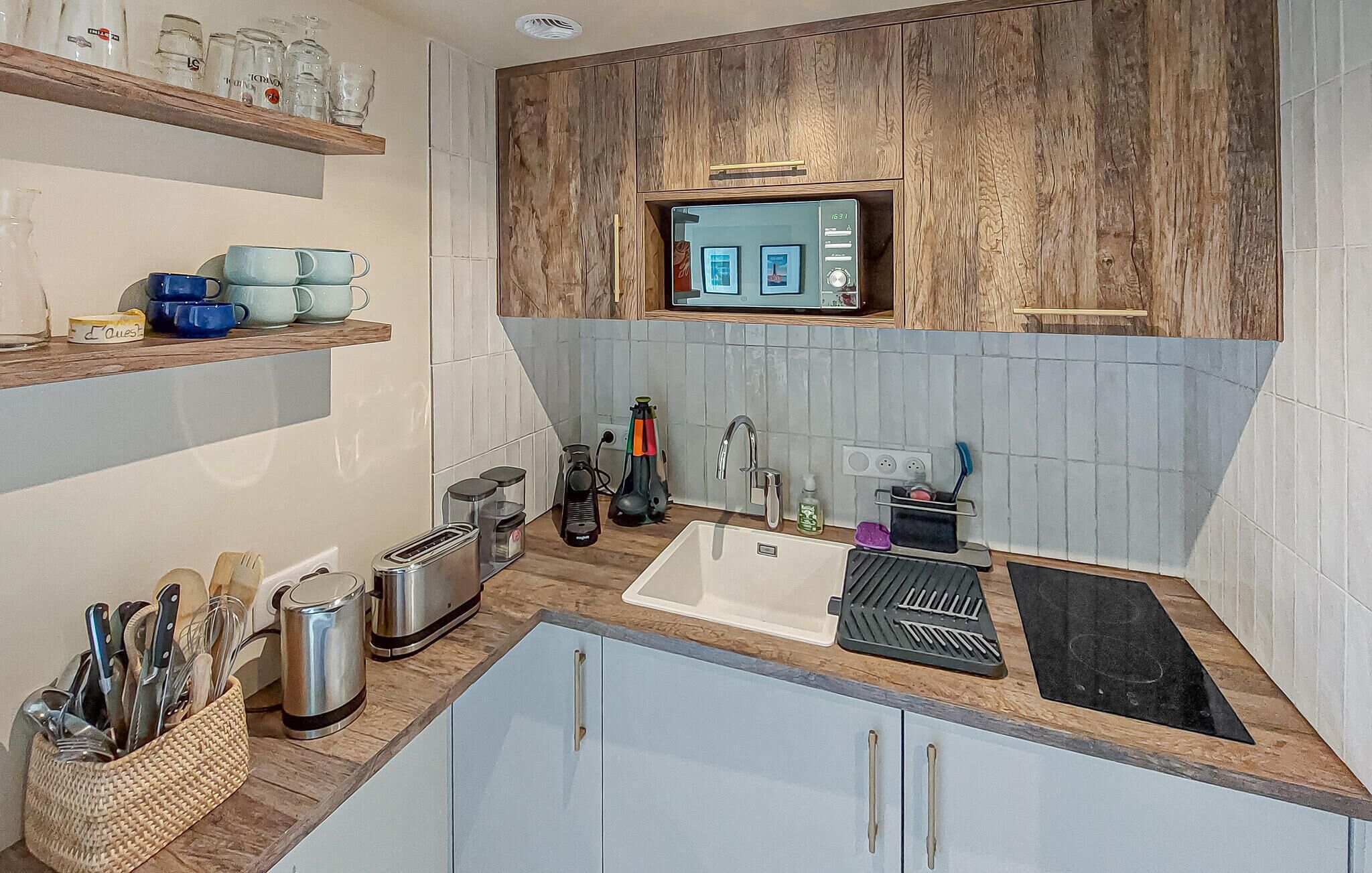 Une cuisine dotée de meubles de rangement en bois, d’un four à micro-ondes encastré, d’un évier et de divers appareils de cuisine.
