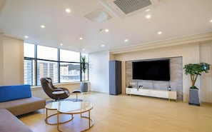 A modern living room with a large TV, comfortable seating, and a view of the city. - Ayana Hotel & Resort (Mokpo)