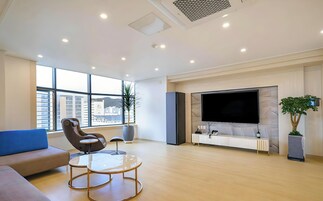 Una sala de estar moderna con un televisor grande, asientos cómodos y vistas de la ciudad.