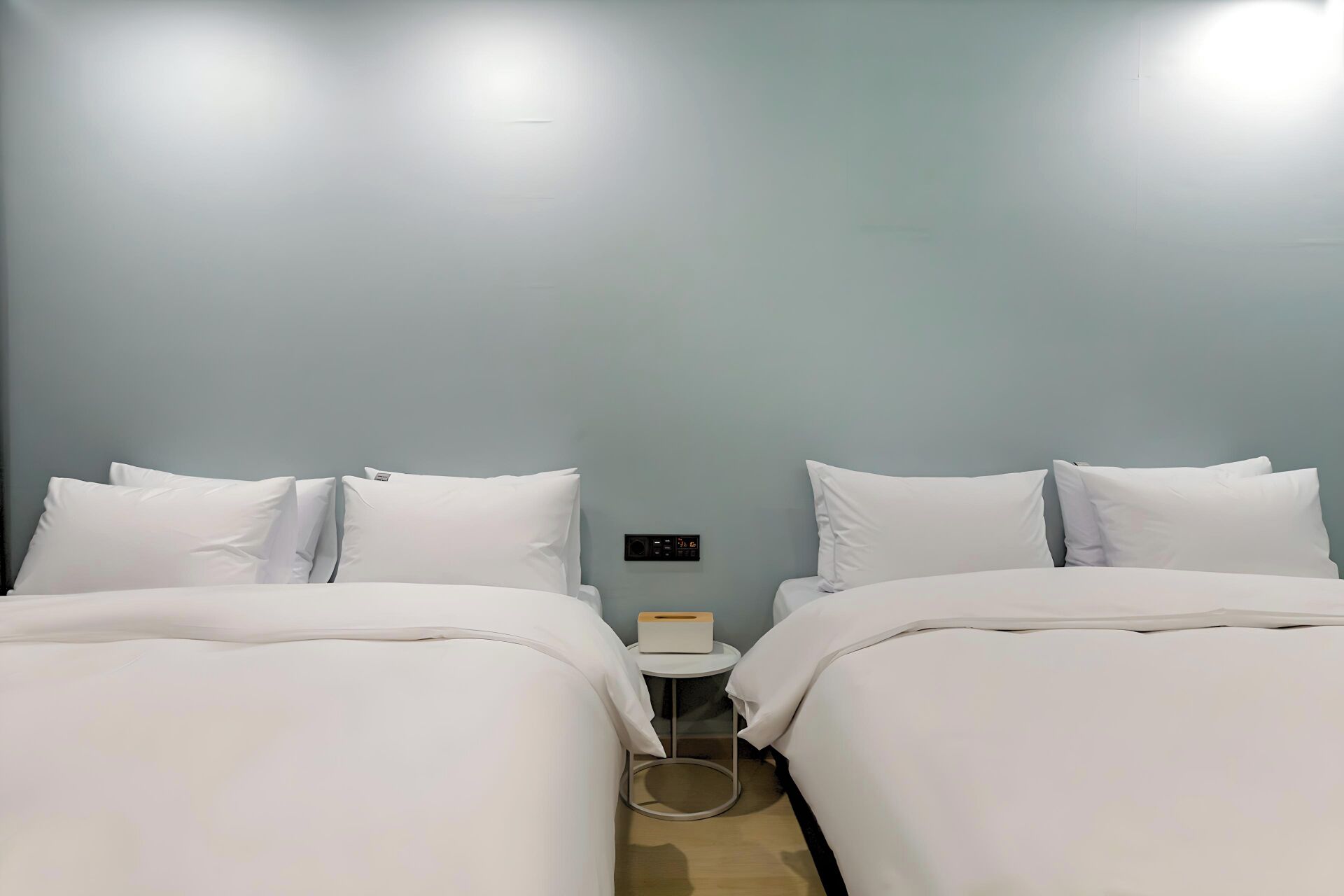 Ein Hotelzimmer mit zwei Betten, einem kleinen Nachttisch und einer an der Wand montierten Steuerung.