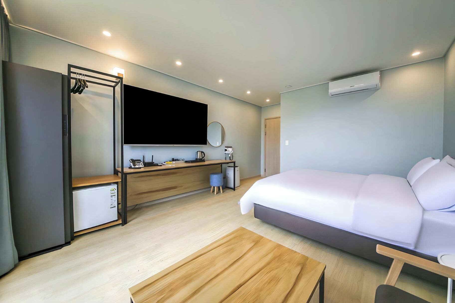 A modern hotel room with a bed, a desk, a wardrobe, and a television.