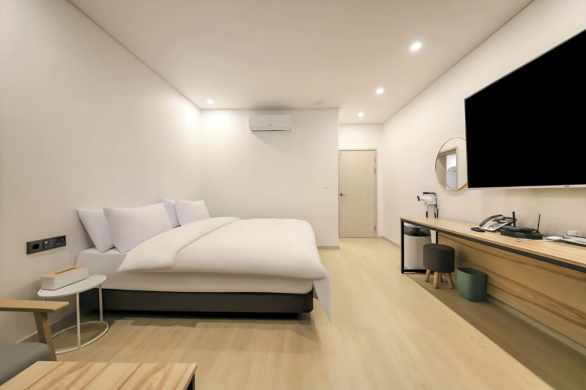 Een moderne hotelkamer met een bed, nachtkastje, bureau en een grote spiegel.
