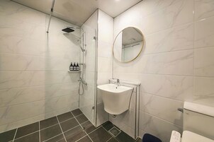 Un baño moderno con ducha, lavamanos e inodoro.
