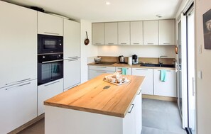 A modern kitchen with white cabinetry, a wooden countertop, and a coffee station. - 2 bedroom amazing apartment in Névez (Névez)