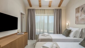 Quarto de hotel com cama, televisão, mesa de cabeceira e janela com cortinas.