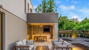 Eine Terrrasse mit Essbereich, Sofas und einem Fernsehbildschirm.