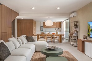 A modern living room with a sectional sofa, a dining area with wooden furniture, and a kitchen with a large island. - Nareo Villa Collection - Villa Arda, Labin, Croatia (Labin)