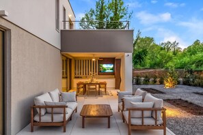 A modern outdoor patio with a dining area, sofas, and a TV screen. - Nareo Villa Collection - Villa Arda, Labin, Croatia (Labin)