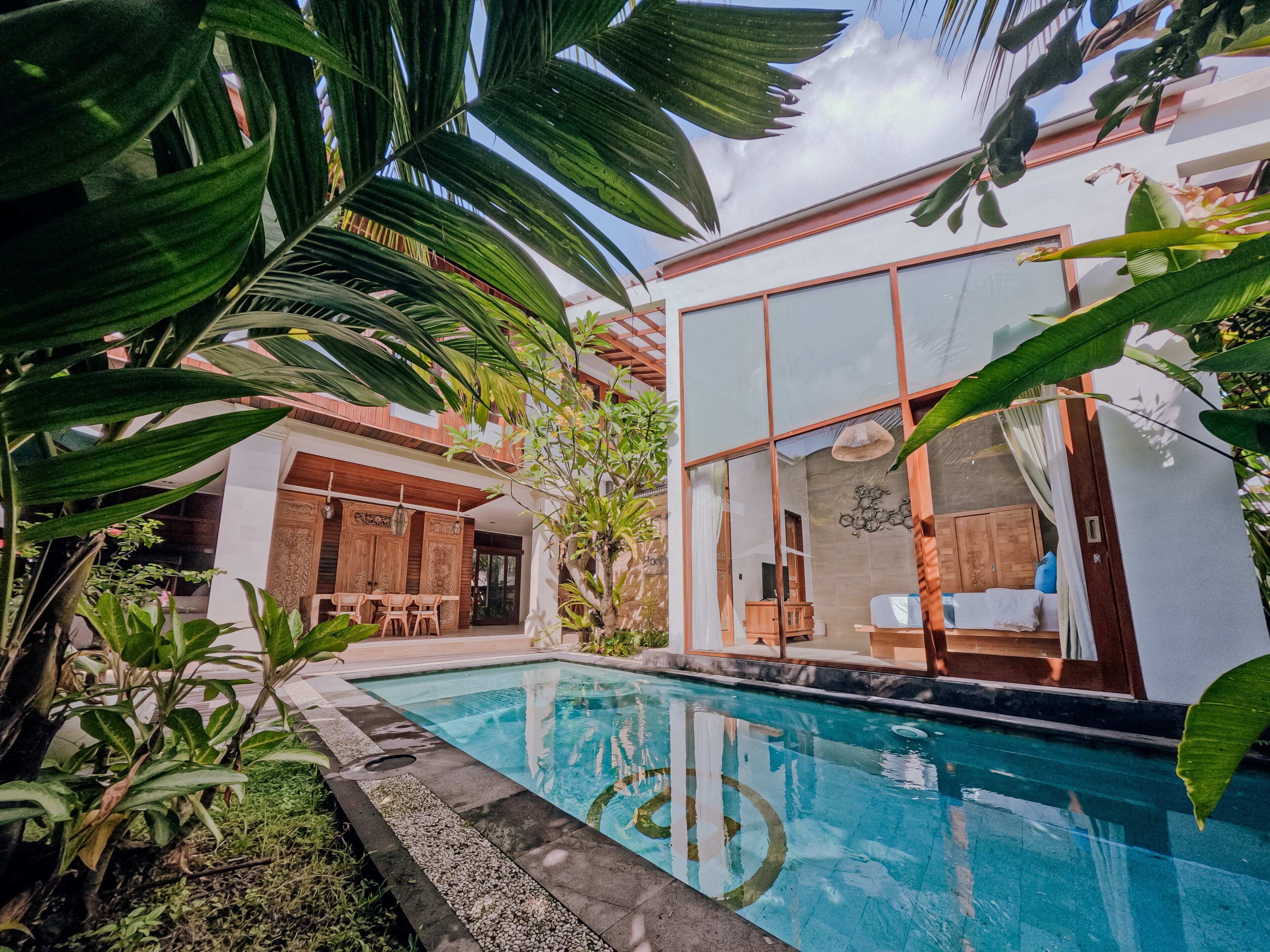 A modern house with a swimming pool, surrounded by lush greenery.