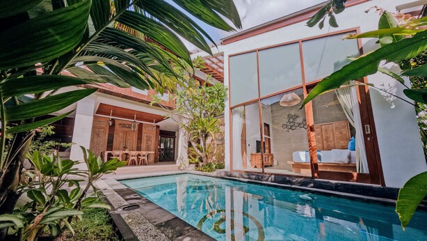 Una casa moderna con piscina, rodeada de exuberante vegetación.