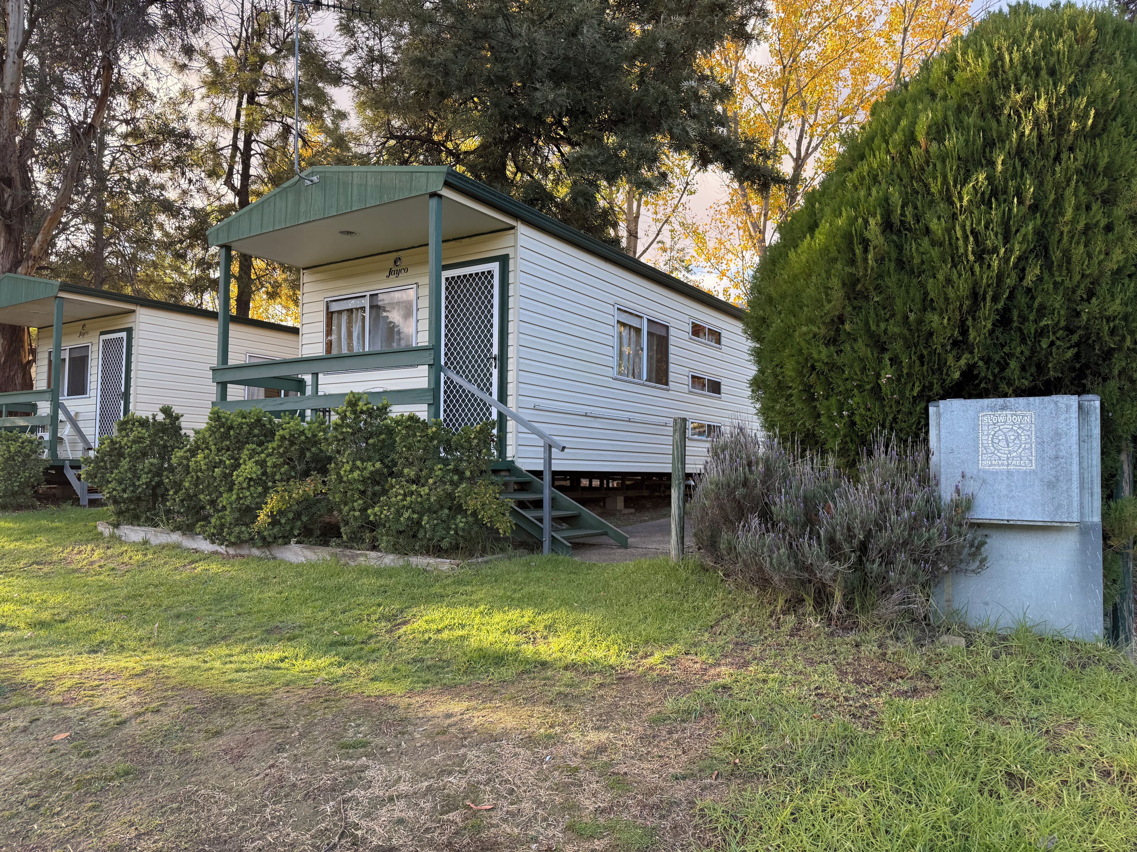 A mobile home with a covered porch, a small front yard, and a mailbox.