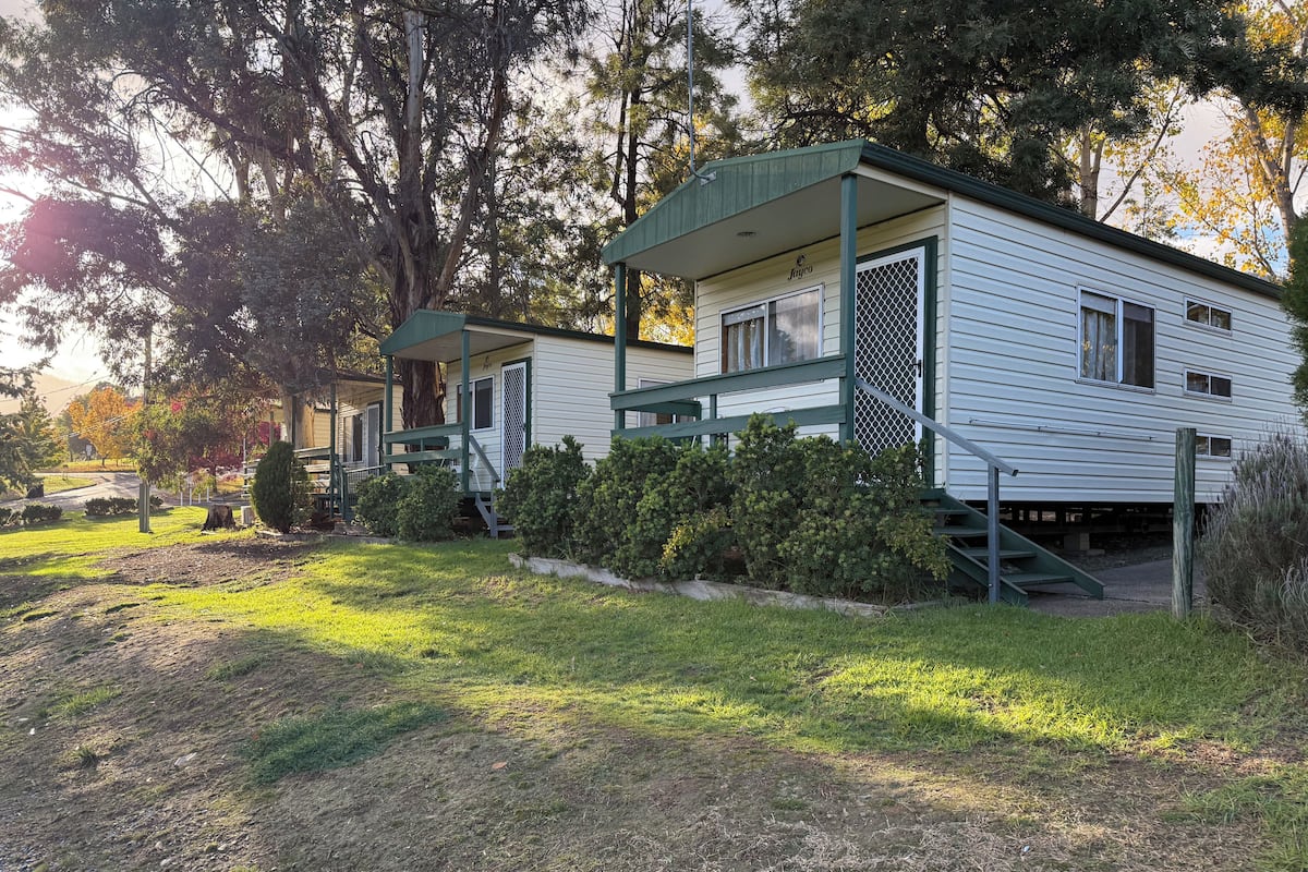 A mobile home with a porch, a covered staircase, and a small front yard.