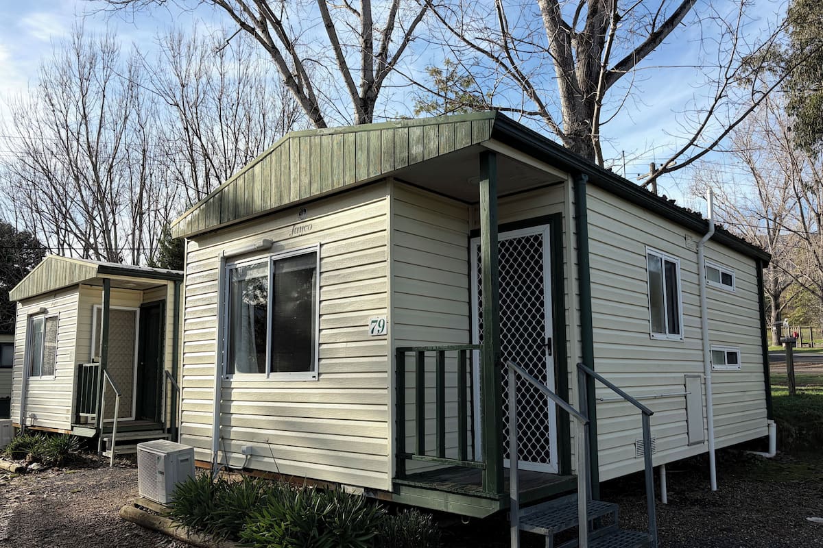 A small, single-story mobile home with a porch, a door with a screen, and a number '79' on the side.