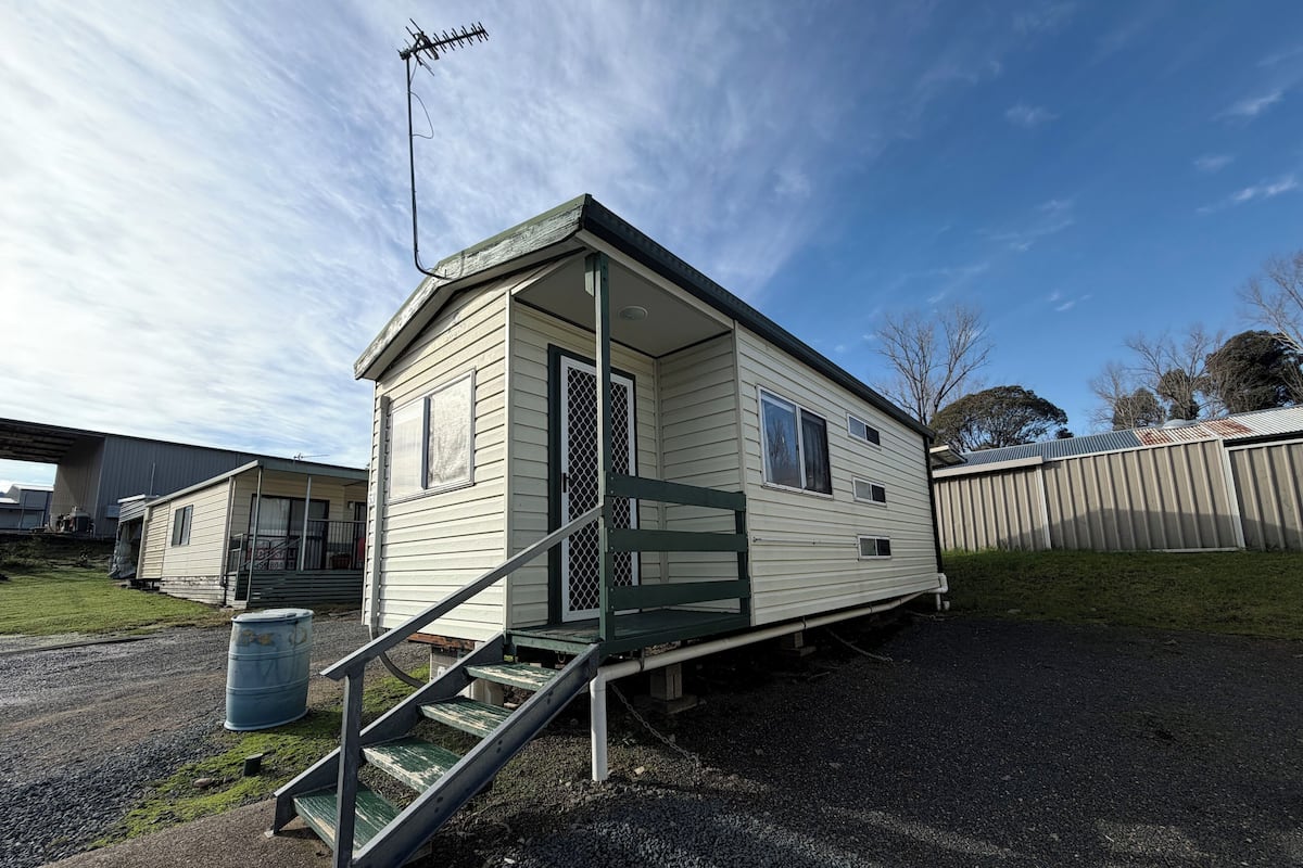 A mobile home with a front porch, a staircase, and a satellite dish.