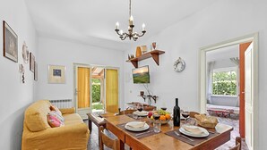 Zona de menjador amb taula de fusta preparada per a dues persones, sofà i televisor penjat a la paret.