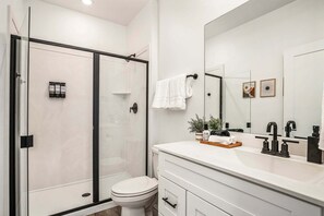 A modern bathroom with a glass shower enclosure, a white toilet, a vanity with a mirror, and a sink. - Skyline 1729, Golf Simulator, Oversized Hot Tub, and Resort Amenities (Washington)