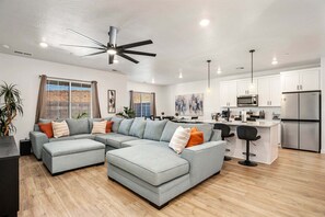 A modern living room with a sectional sofa, a dining area, and a kitchen with white cabinets and stainless steel appliances. - Skyline 1729, Golf Simulator, Oversized Hot Tub, and Resort Amenities (Washington)