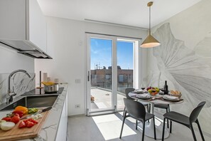 Eine moderne Küche mit einem großen Fenster, einem Essbereich mit Tisch für zwei Personen und Blick auf die Stadt.