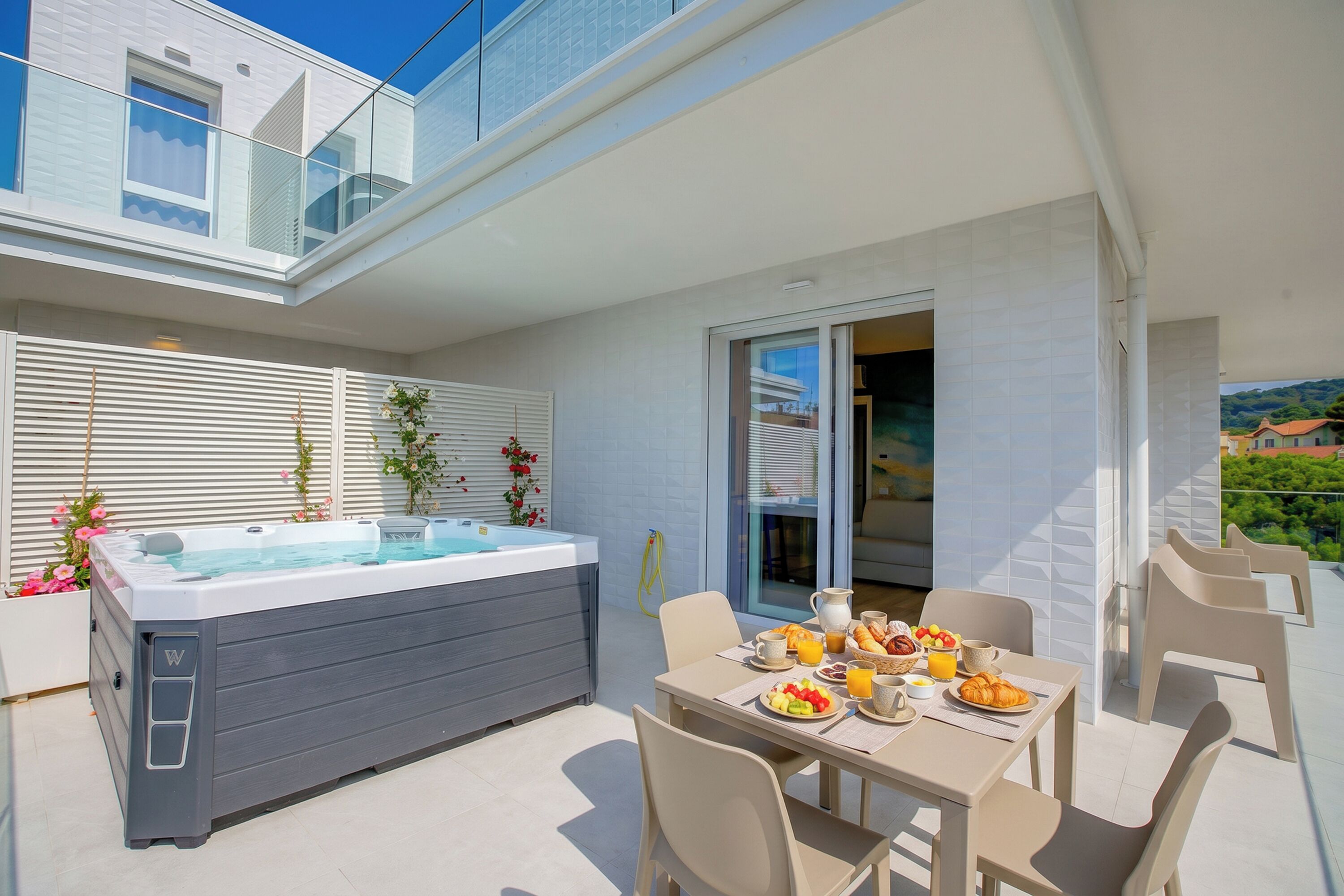 Eine moderne Außenpatio mit Whirlpool, Esstisch, Stühlen und Blick auf ein Wohngebäude.