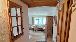 Un corridoio in legno con una porta, una finestra e vista su una sala da pranzo.