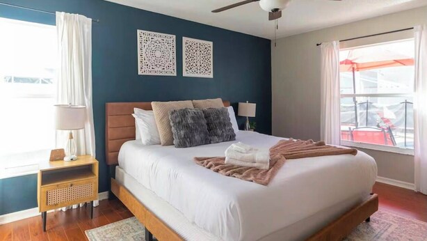 Une chambre à coucher comprenant un lit, une table de chevet, un ventilateur de plafond et des éléments décoratifs sur les murs.