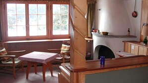 A cozy room with a fireplace, a table with a checkered tablecloth, and a window with curtains.