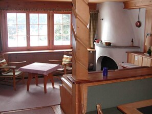 A cozy room with a fireplace, a table with a checkered tablecloth, and a window with curtains.