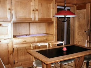 A wooden kitchen with a table, chairs, and a red hanging light fixture.