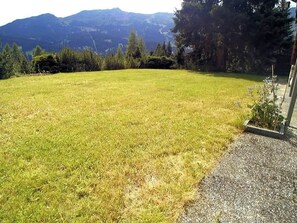 A grassy yard with a gravel path and a building on the right.