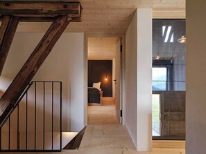 A narrow hallway with a wooden staircase on one side and a bed with a hanging light in the background. - Alphütte Briula Appartement/Fewo, Dusche, WC, 3 Schlafräume by Interhome (Valbella)