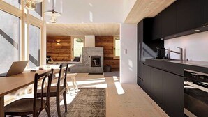 A modern kitchen with dark cabinetry, a built-in oven, and a dining area with a wooden table and chairs. - Alphütte Briula Appartement/Fewo, Dusche, WC, 3 Schlafräume by Interhome (Valbella)