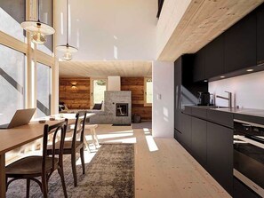 A modern kitchen with dark cabinetry, a built-in oven, and a dining area with a wooden table and chairs. - Alphütte Briula Appartement/Fewo, Dusche, WC, 3 Schlafräume by Interhome (Valbella)