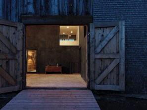 A rustic barn-style entrance with a wooden door, a small desk with a lamp, and a view of the interior. - Alphütte Briula Appartement/Fewo, Dusche, WC, 3 Schlafräume by Interhome (Valbella)