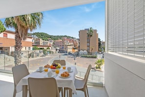 A balcony with a table set for breakfast, overlooking a street with buildings and a hill. - Nua Boutique Apartaments 13 Towncentre, Finale Ligure, Italy (Finale Ligure)