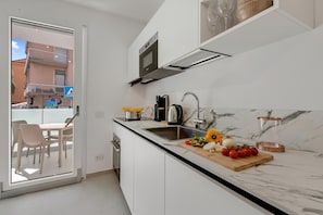 Eine moderne Küche mit Backofen, Kaffeemaschine und Schneidebrett mit Gemüse.