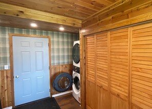 Una sala de bugaderia amb parets de fusta, una porta i dues rentadores.
