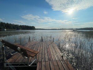 Eine Holzsteg erstreckt sich über ruhiges Wasser, am Ende befindet sich eine Bank.