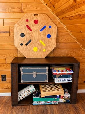 A wooden board game with various pieces and a storage unit with games and a chess set. - The Narrows on Lawrence Lake
Privacy, Hot Tub, Beach, Dock, Quick Trail Access (Outing)