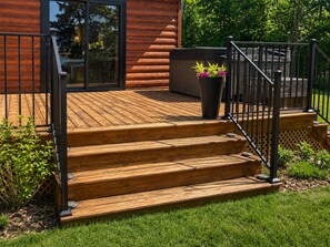 A wooden deck with steps leading to a glass door, surrounded by greenery. - The Narrows on Lawrence Lake
Privacy, Hot Tub, Beach, Dock, Quick Trail Access (Outing)