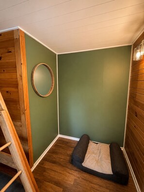 A corner room with a wooden ladder, a circular mirror, and a cushioned bench. - The Narrows on Lawrence Lake
Privacy, Hot Tub, Beach, Dock, Quick Trail Access (Outing)