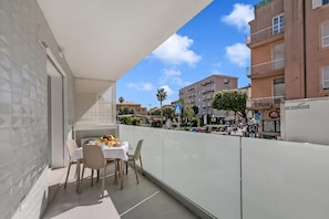 Ein Balkon mit Esstisch, Blick auf die Straße und Gebäude im Hintergrund.