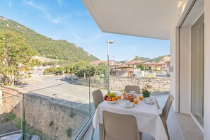 Ein Balkon mit Frühstückstisch, der auf einen Parkplatz und eine Berglandschaft blickt.