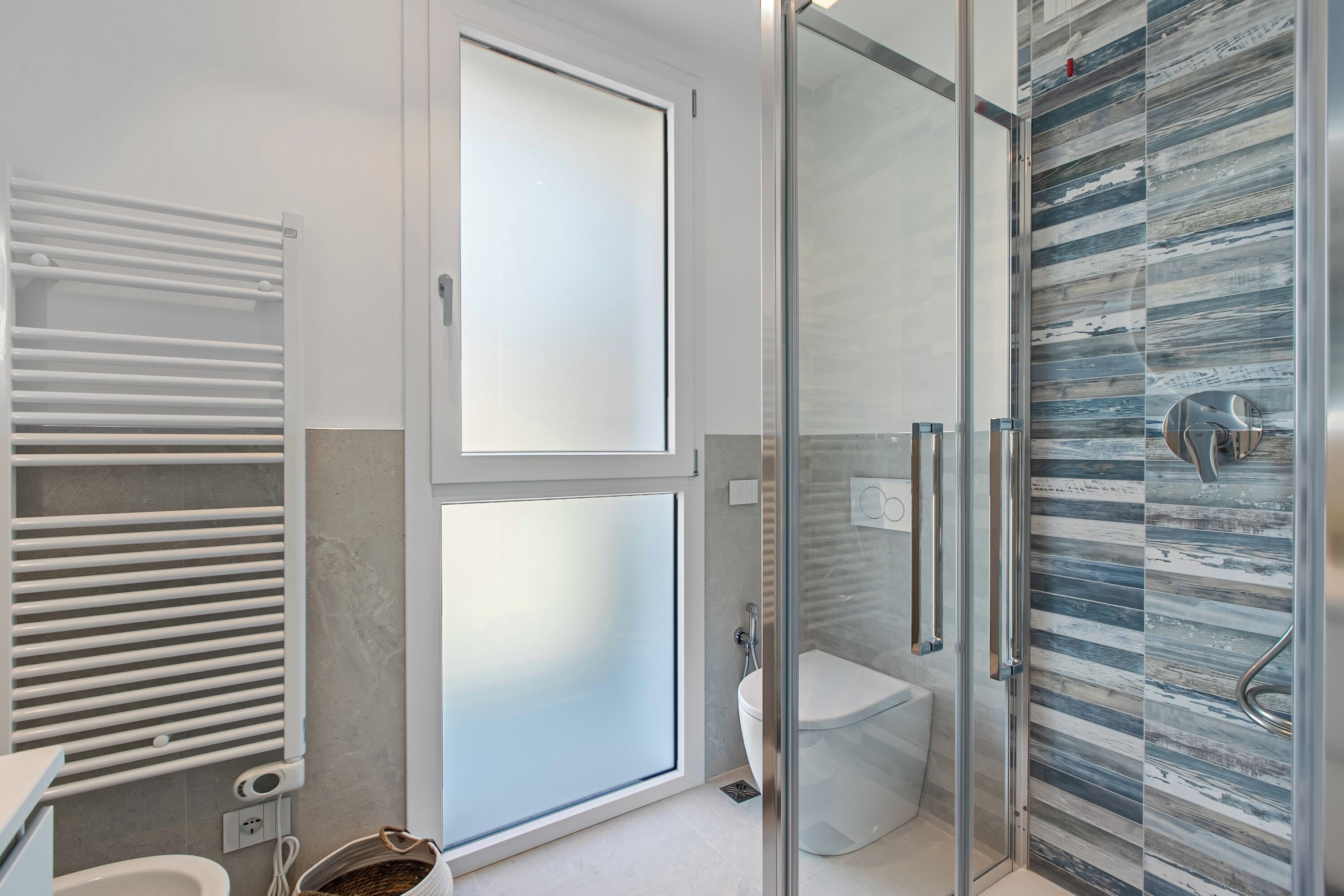 Un baño moderno con cabina de ducha de vidrio, inodoro y toallero.