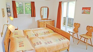 Una camera da letto con un letto, una cassettiera, uno specchio, una sedia e una finestra.