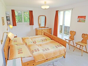 Ein Schlafzimmer mit Bett, Kommode, Spiegel, Stuhl und Fenster.